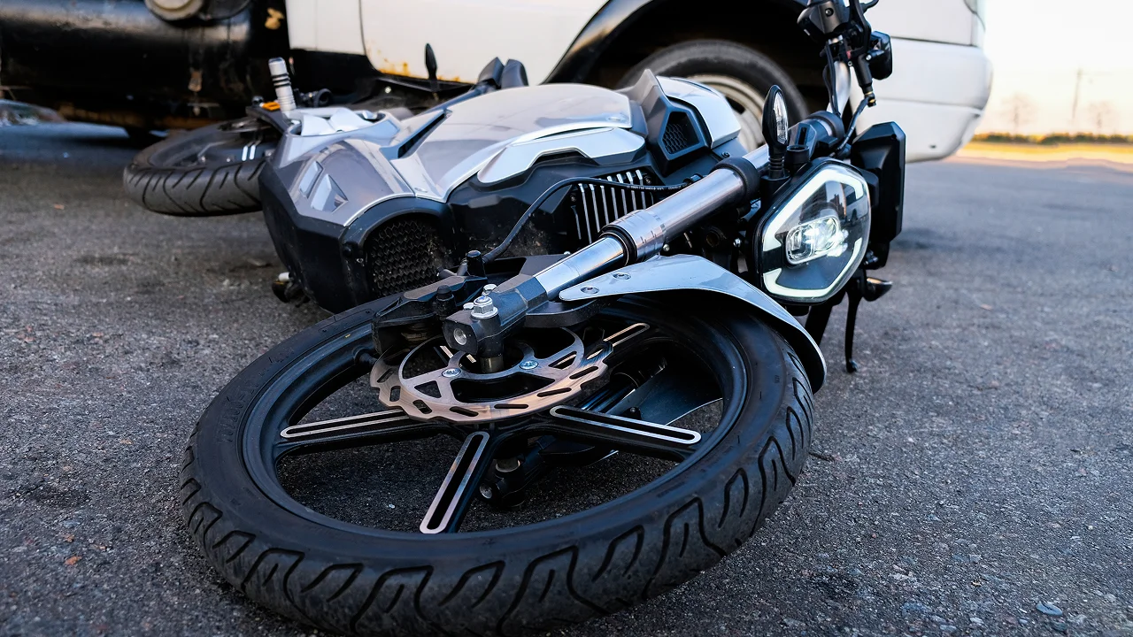 Damaged motorcycle lying on its side on the road after an accident.