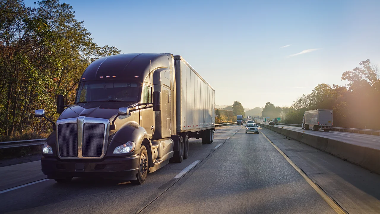 A semi-truck driving down an open highway during daylight.