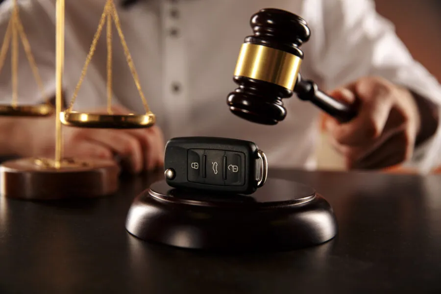 Close up of judge gavel and car keys over soundboard on white