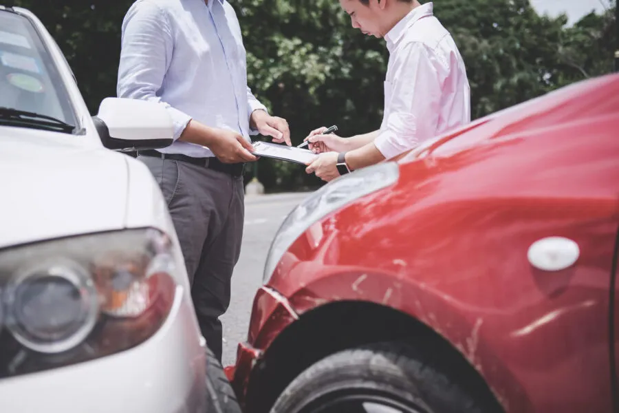 Insurance Agent examine Damaged Car and customer filing signature on Report Claim Form process after accident,