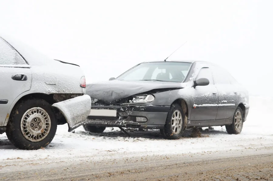 Two cars involved in a rear-end collision on a snow-covered road.