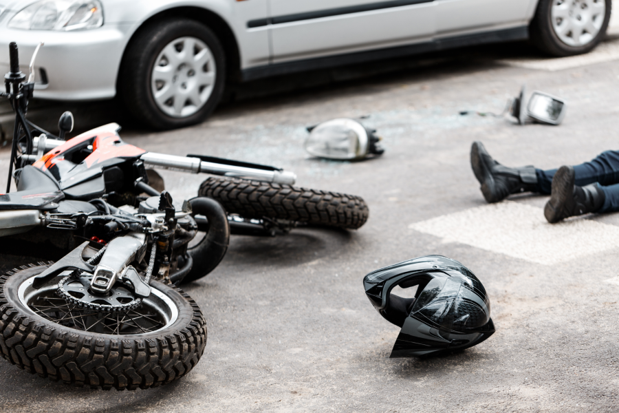 Legs of a person lying on the road after a motorcycle and car accident