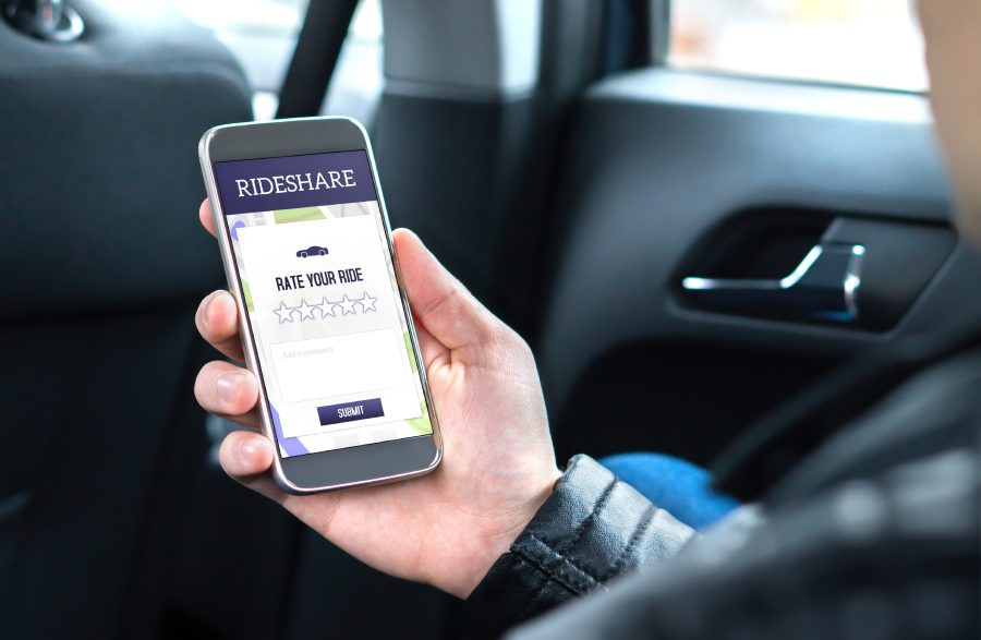 Ride share customer and passenger sitting in the backseat of a car while using the rideshare application in smartphone to give rating to the driver.