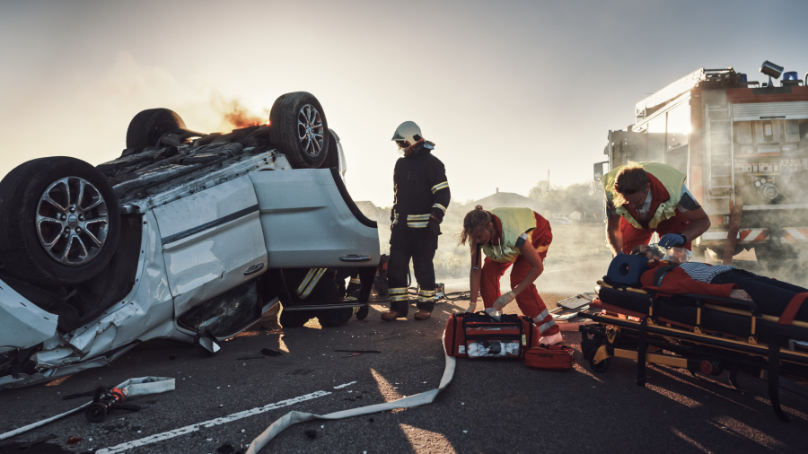 On the Car Crash Traffic Accident: Paramedics and Firefighters Rescue Injured Trapped Victims. Medics give First Aid to Female on Stretchers. Firemen Use Hydraulic Cutters Spreader to Open Vehicle