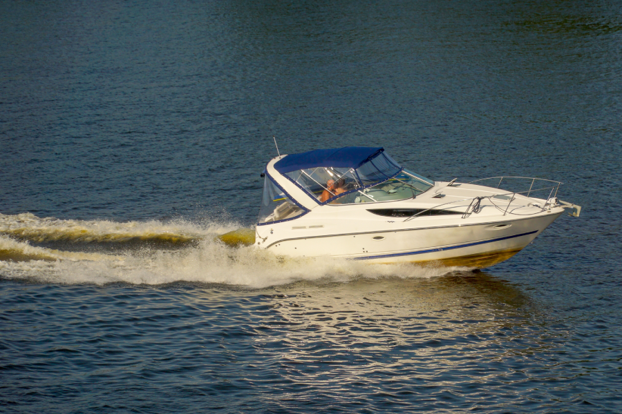 A luxury speedboat sails through the water, raising a wave and scattering spray and foam