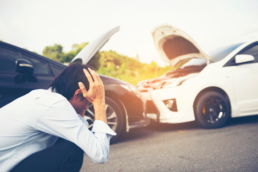 Young man rubbing neck in pain from whiplash injury standing by damaged car after traffic accident car traffic accident collision