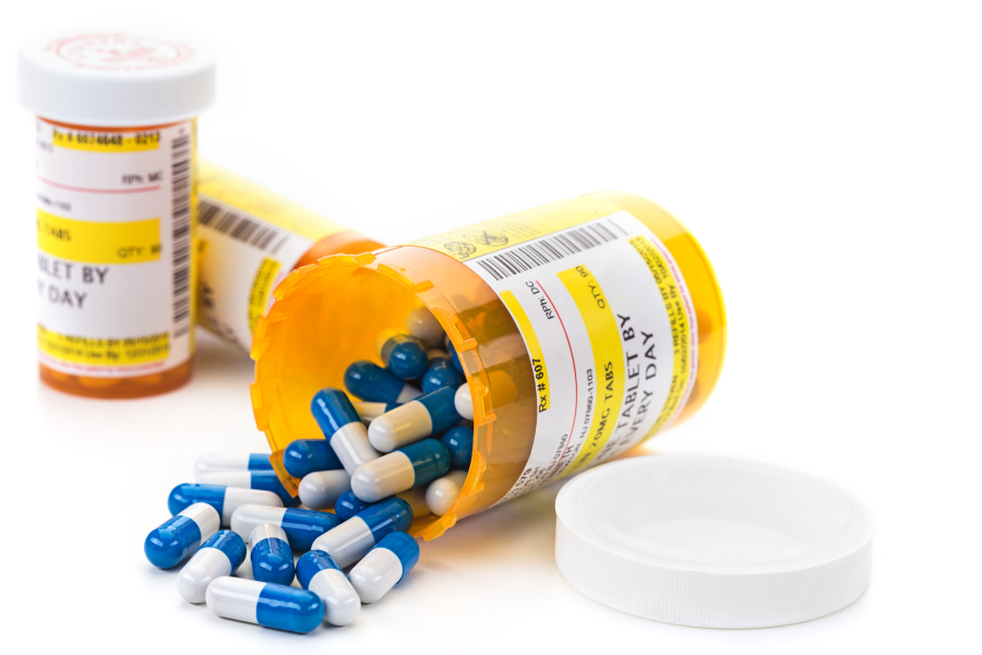 Prescription medication cascading out of orange pharmacy vials isolated on white