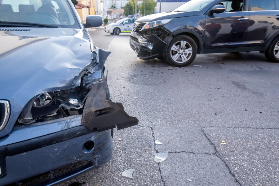 road with two cars that have had an accident with material damage to both cars and a police car blocking traffic