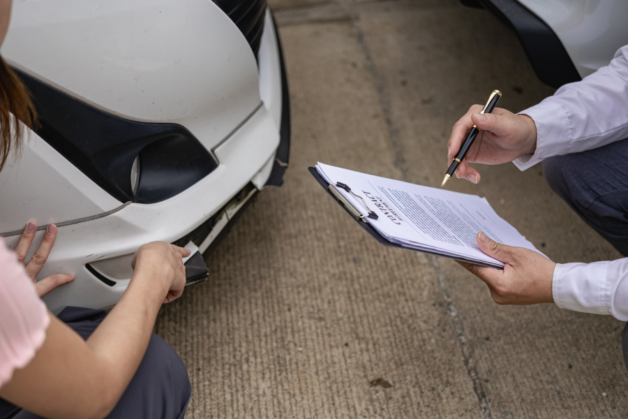 Car claim process Insurance agent after car accident writes on clipboard while inspecting car after accident claim is evaluated and processed Close-up pictures