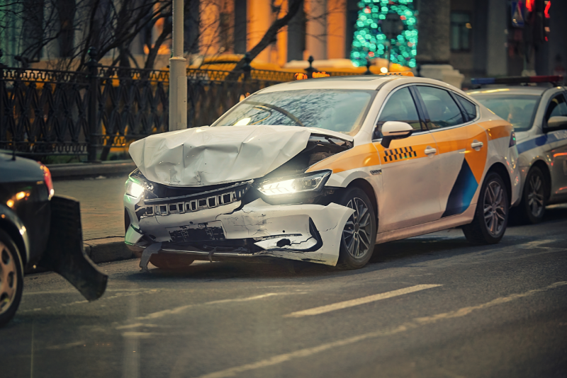 Damaged car with smashed front end at roadside after traffic accident. Broken taxi car with visible damage.