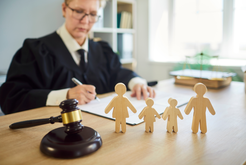 Judge woman in professional outfit black robe writing reviewing family jurisprudence documents in court room desk,